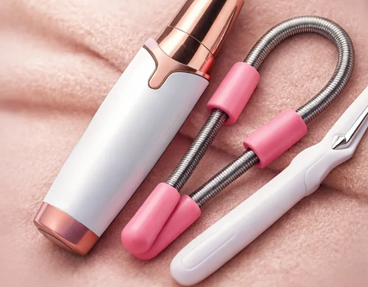 Épilateur visage, épilateur à ressort et pince à épiler posés sur un tissu rose